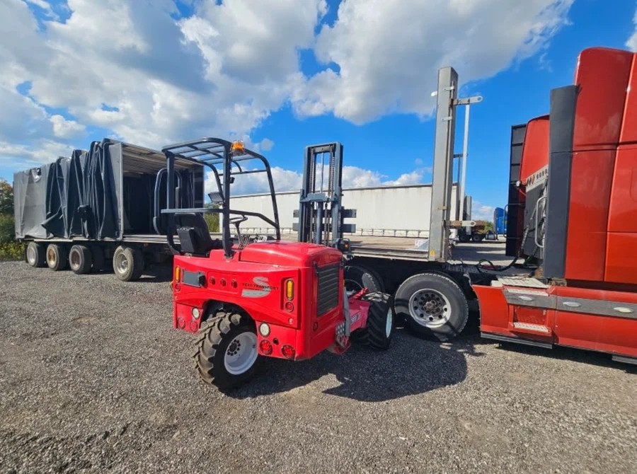 Red piggyback forklift next to a Conestoga truck Red piggyback forklift next to a Conestoga truck