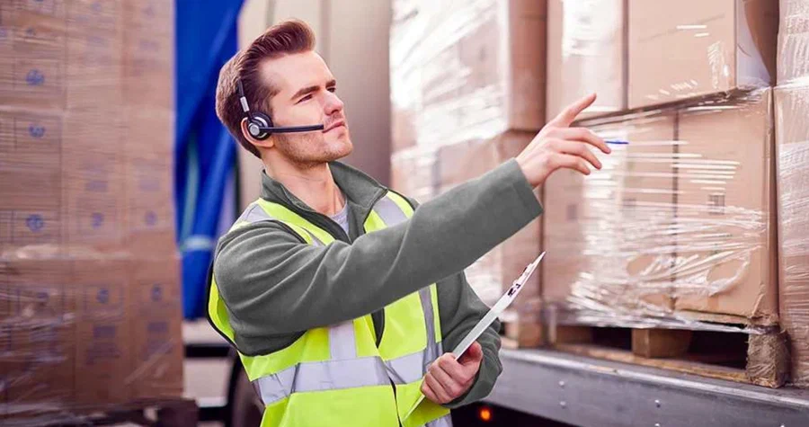 A man wearing a safety vest in a warehouse