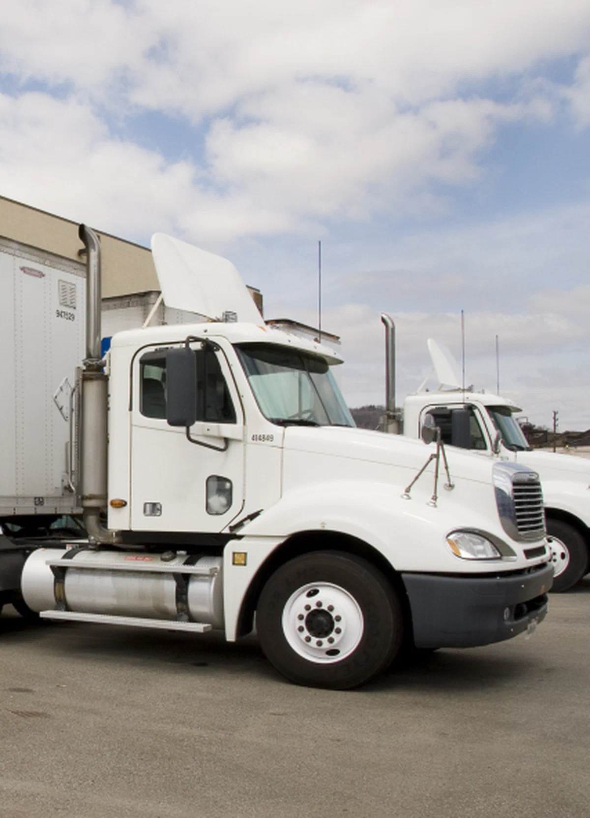 Semi trucks with enclosed trailers parked at a freight facility Semi trucks with enclosed trailers parked at a freight facility