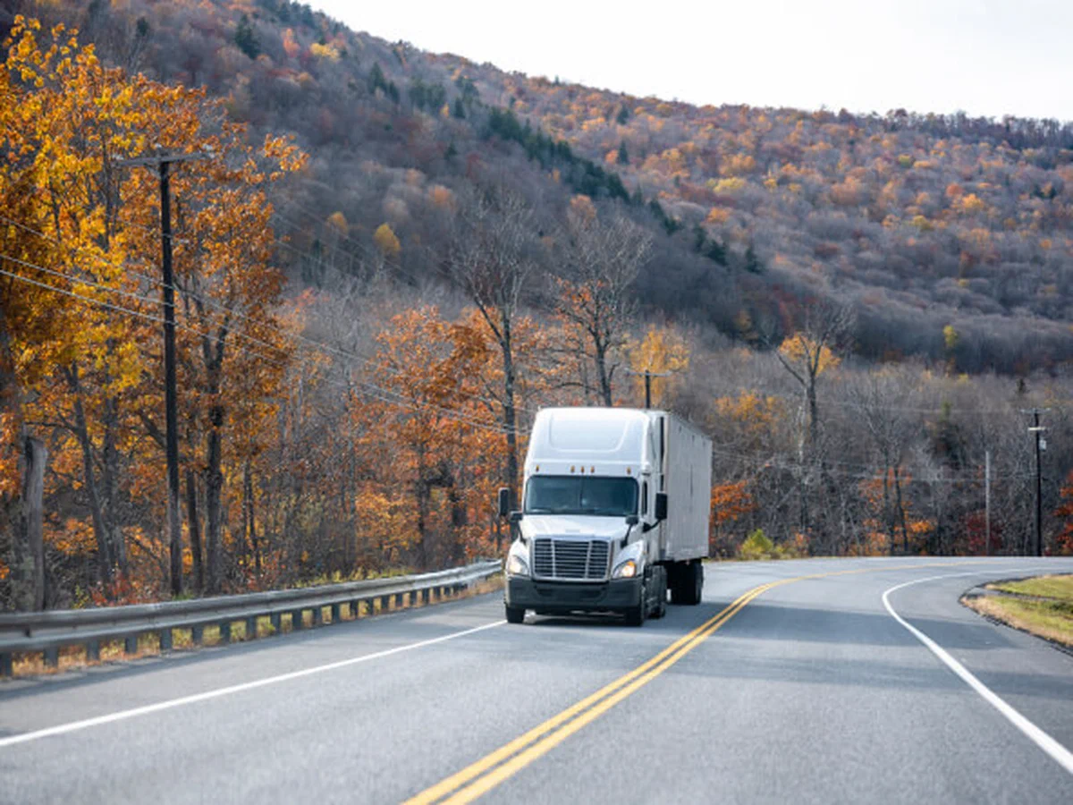 A freight truck driving on a roadway. A freight truck driving on a roadway.